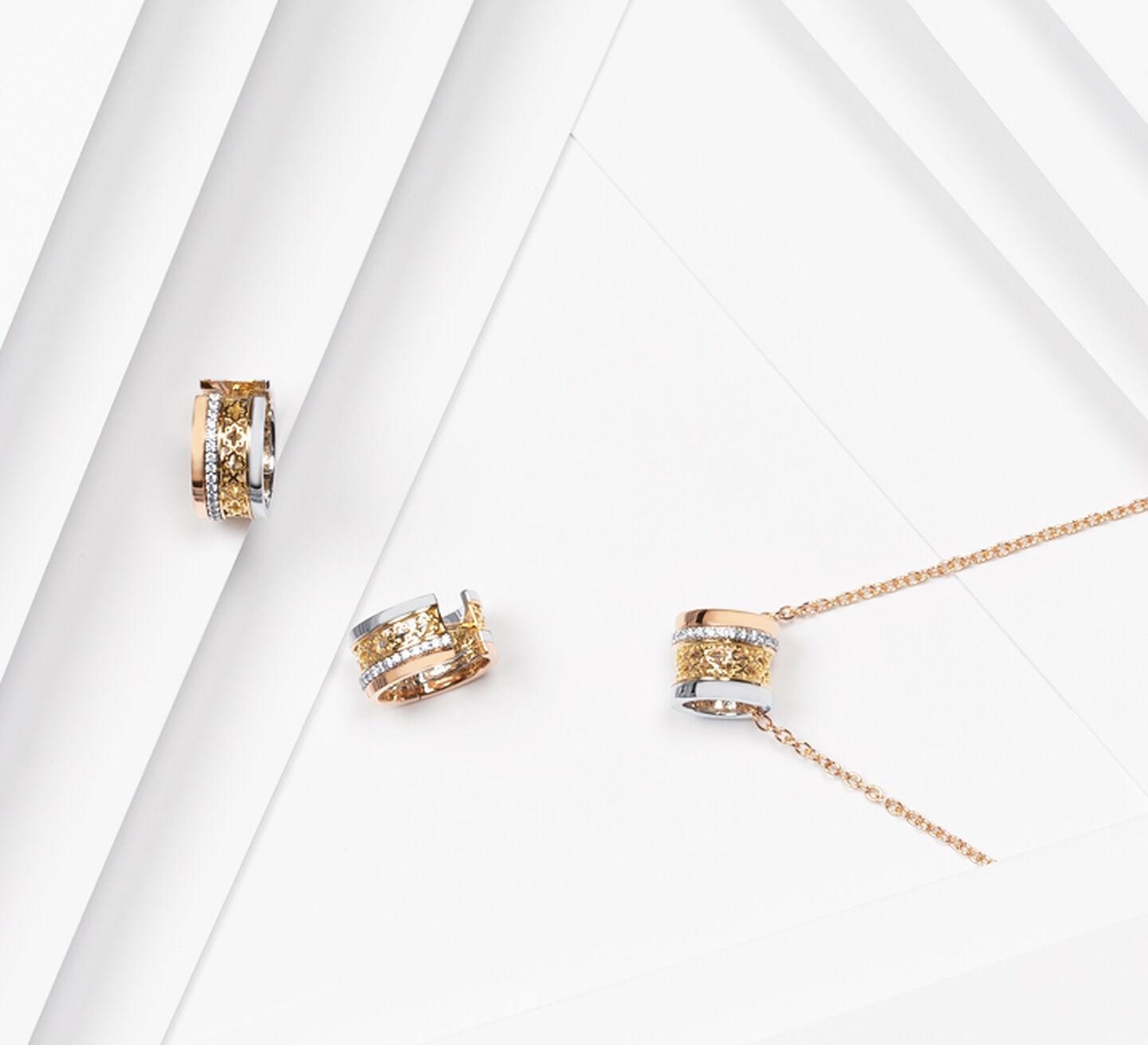 Tri-gold earrings beside a gold necklace with a matching tri-gold pendant